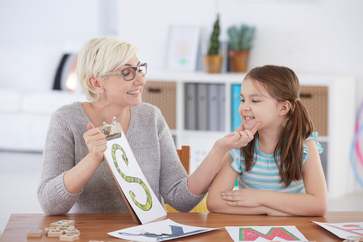 Woman helping teach child who has speech language disorder