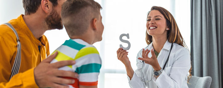 Pediatric speech pathologist working with young patient and father