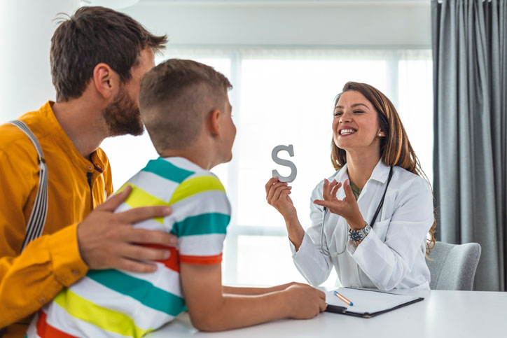 Pediatric speech pathologist working with young patient and father